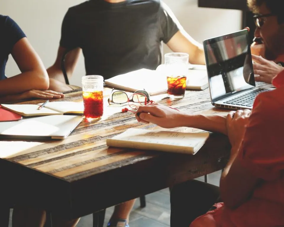 Four founders working through documents and a laptop around a wooden table